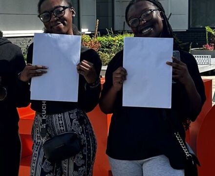 3 students in front of sign